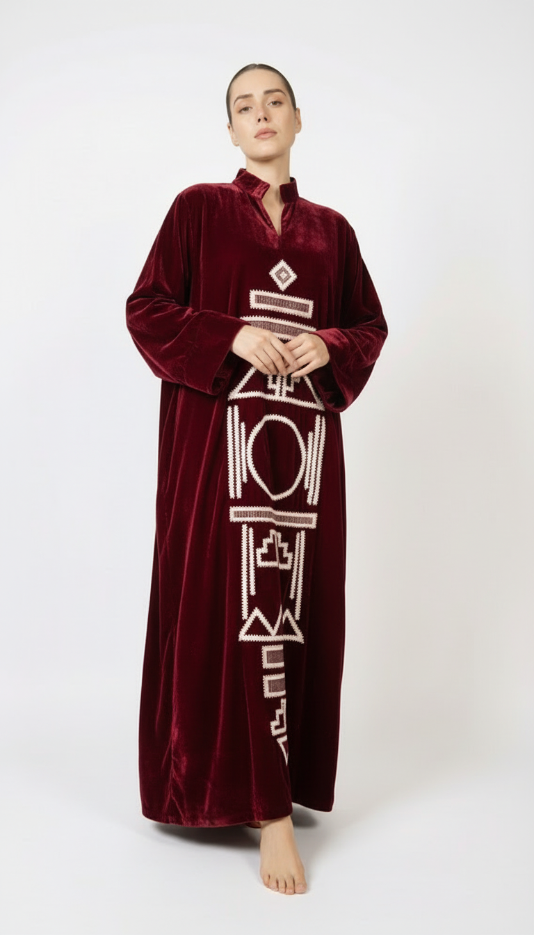 Woman wearing a burgundy velvet dress with white patterns on a white background