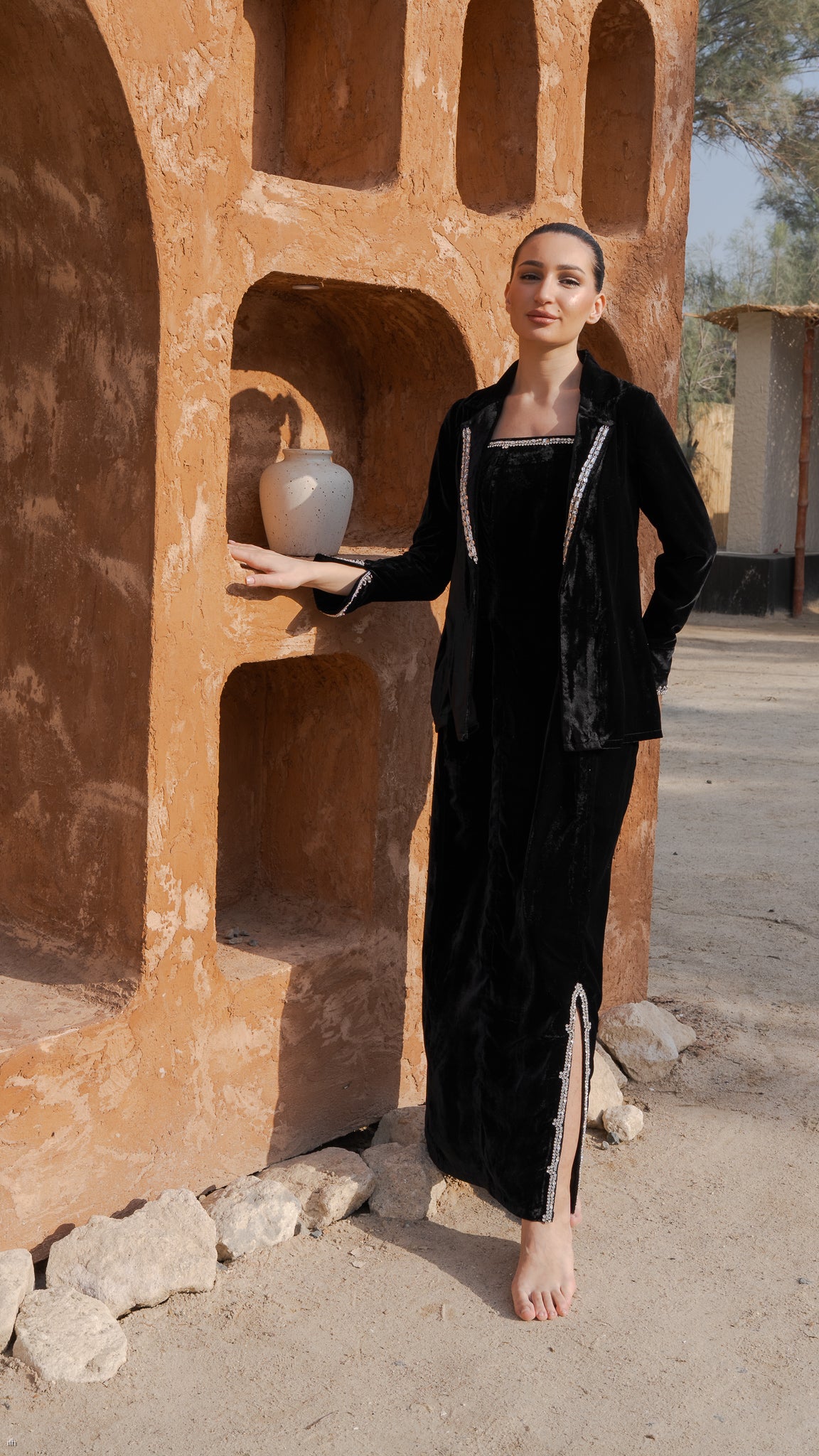 Woman in a black outfit standing in front of an orange architectural structure.