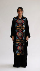 Woman wearing a black dress with a colorful geometric pattern on a white background