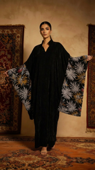 Woman holding a floral-patterned fabric in a room with patterned rugs.