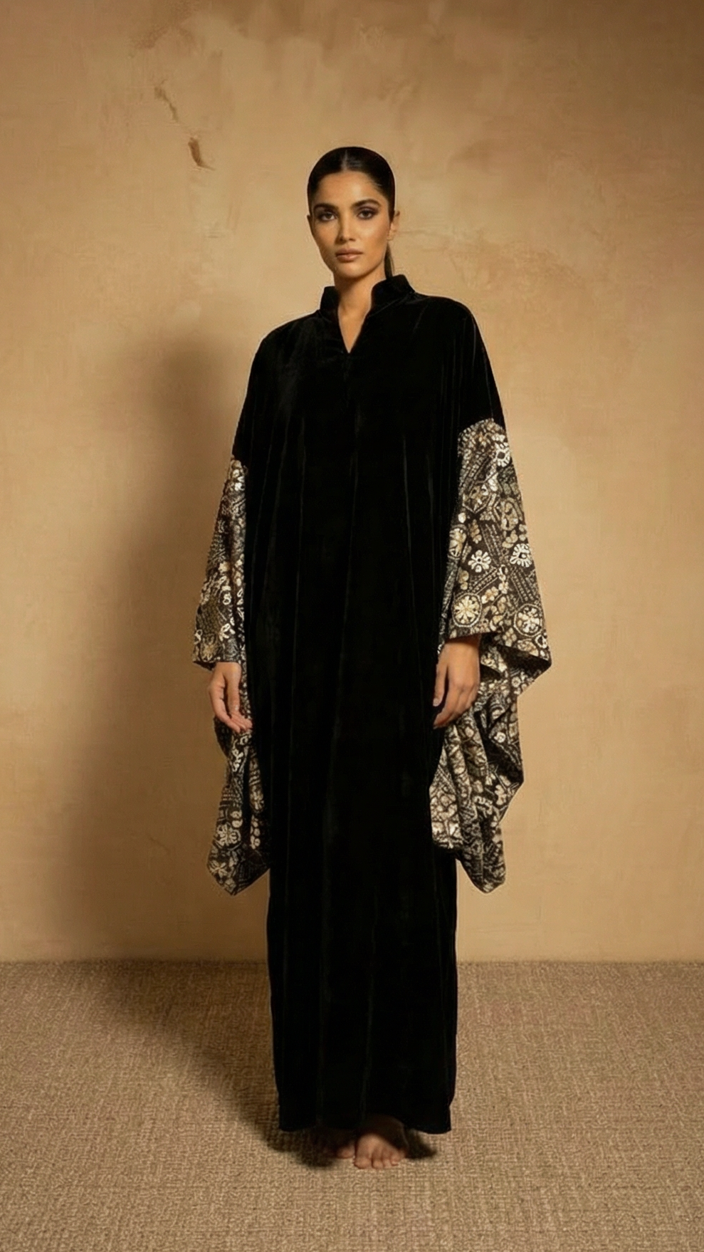 Woman wearing a black dress with floral sleeves against a beige background