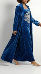 Woman wearing a blue velvet robe with floral embroidery on a white background